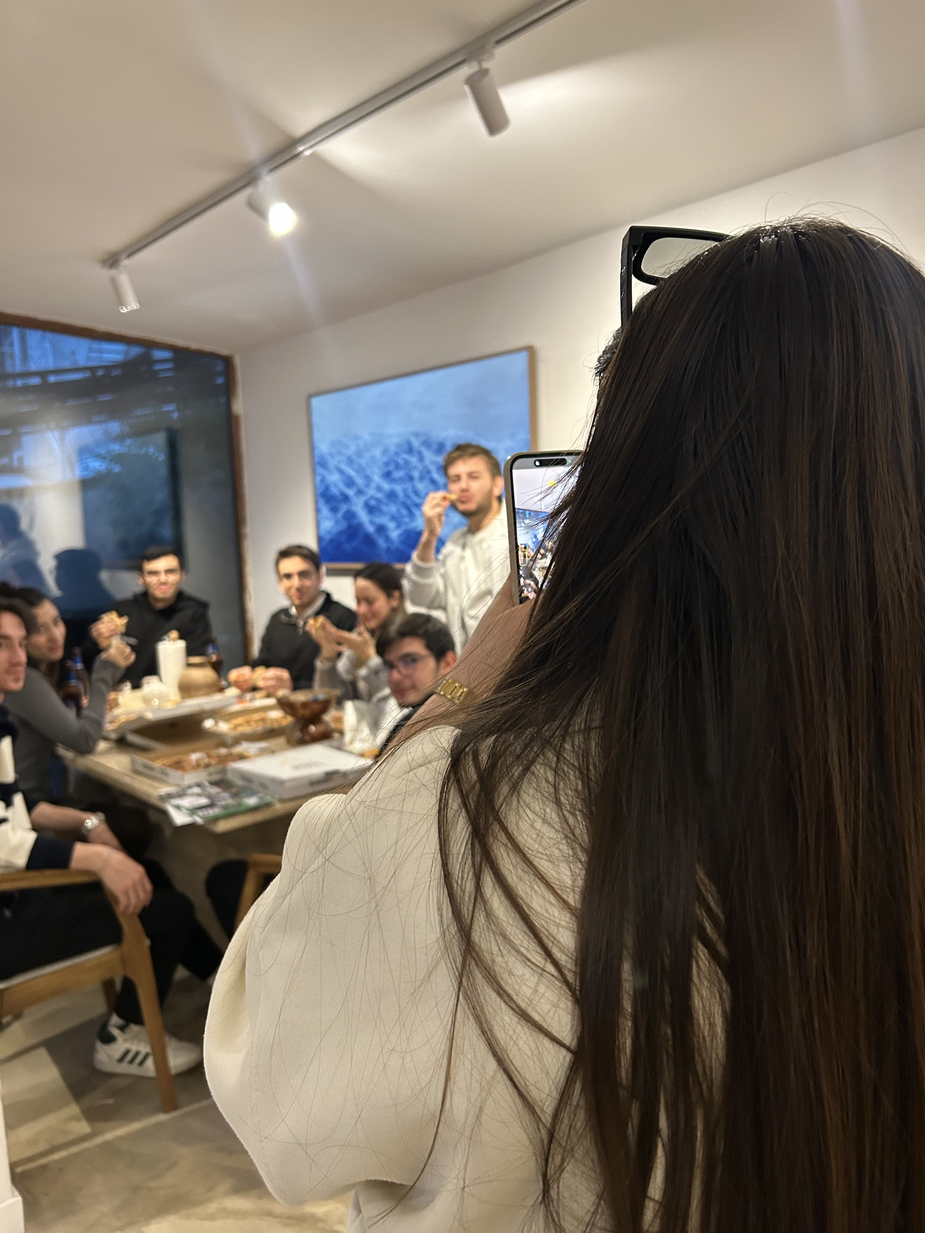 Tera Map Türkiye İstanbul etkinlik eventi Foligno Italia Tera Holding — Tera Holding İstanbul team pizza party eventi gathering photographed from behind a smartphone as colleagues celebrate a collaborative Tera Map office etkinlik in Türkiye